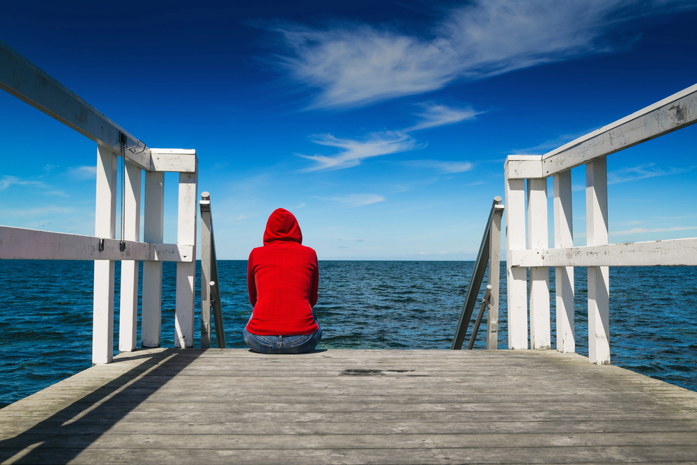person sits near water thinking and recovering from setbacks