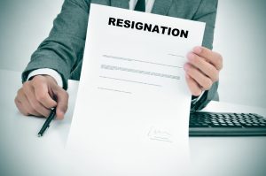 a man in suit in his desk showing a figured signed resignation document