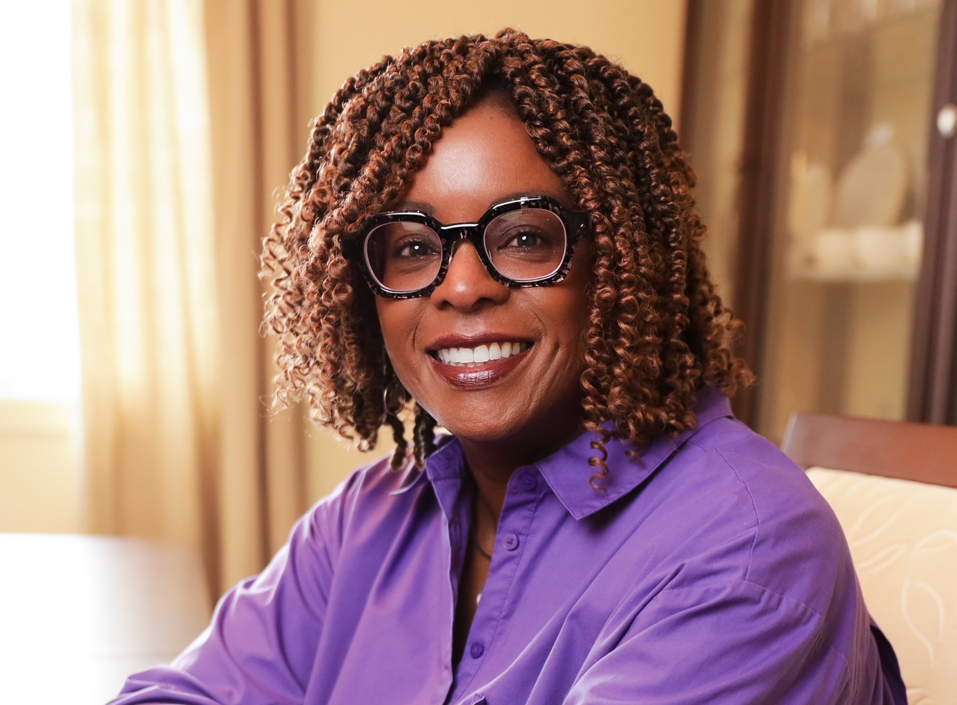 Dr Helen Ofosu wearing a purple blouse and black speckled glasses